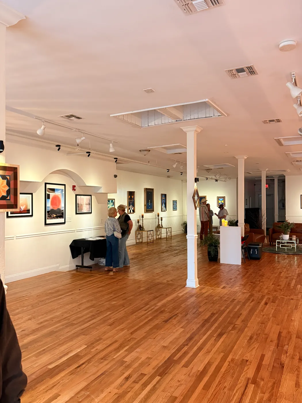 Visitors looking at framed artwork hung along the studio walls during an exhibition